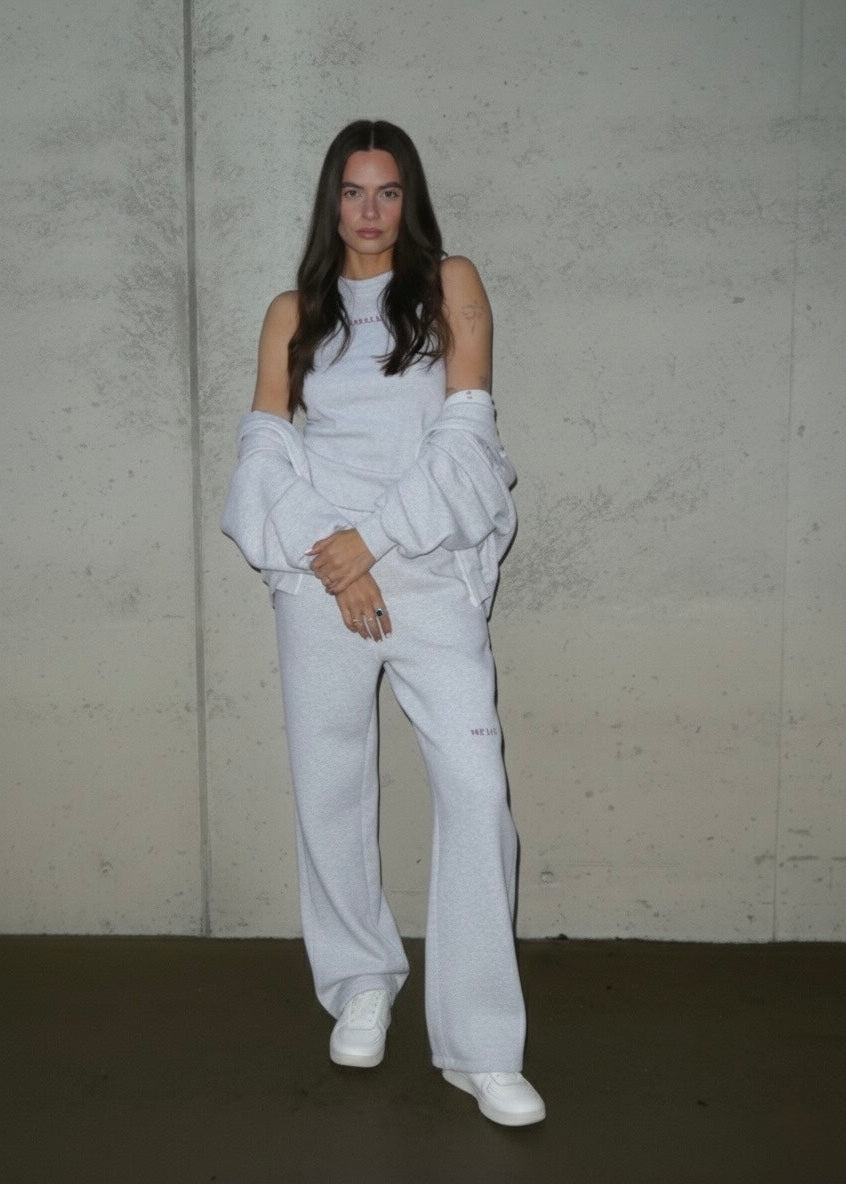 Person wearing a white handmade leisure outfit with a plain background. 