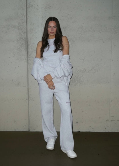 Person wearing a white handmade leisure outfit with a plain background. 
