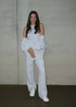 Person wearing a white handmade leisure outfit with a plain background. 